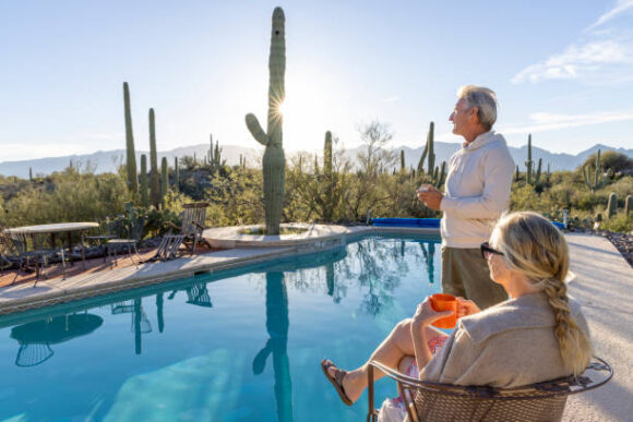 Mature Couple Relax At Desert Swimming Pool And Enjoy Hot Beverage